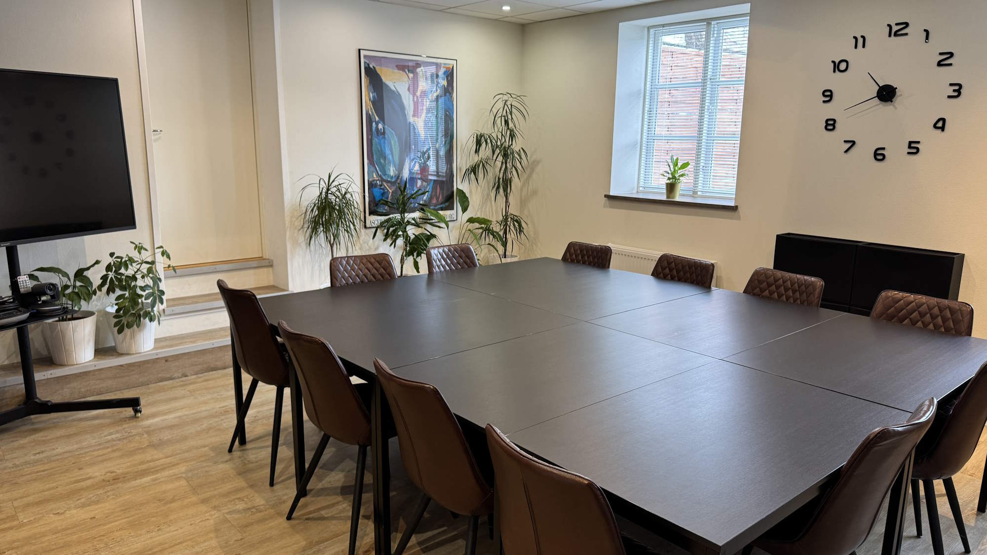 Der er en 65" skærm på et mobilt stativ. 